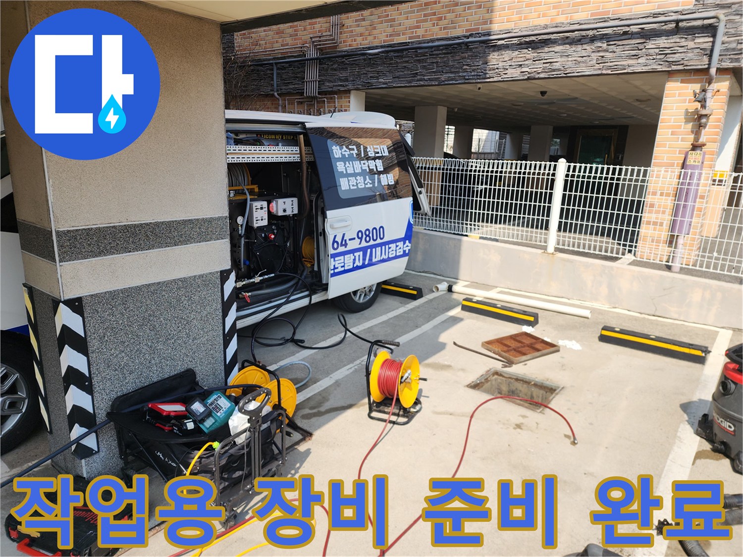차량 뒷부분에서 고압 세척 호스와 관련 장비를 꺼내는 장면입니다.