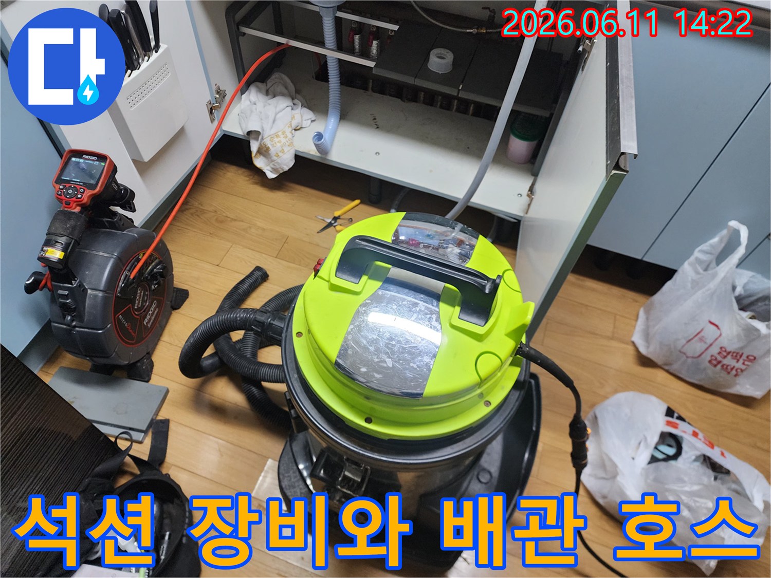 싱크대 하부장 작업 공간에 배치된 석션기와 연결된 배수 호스
