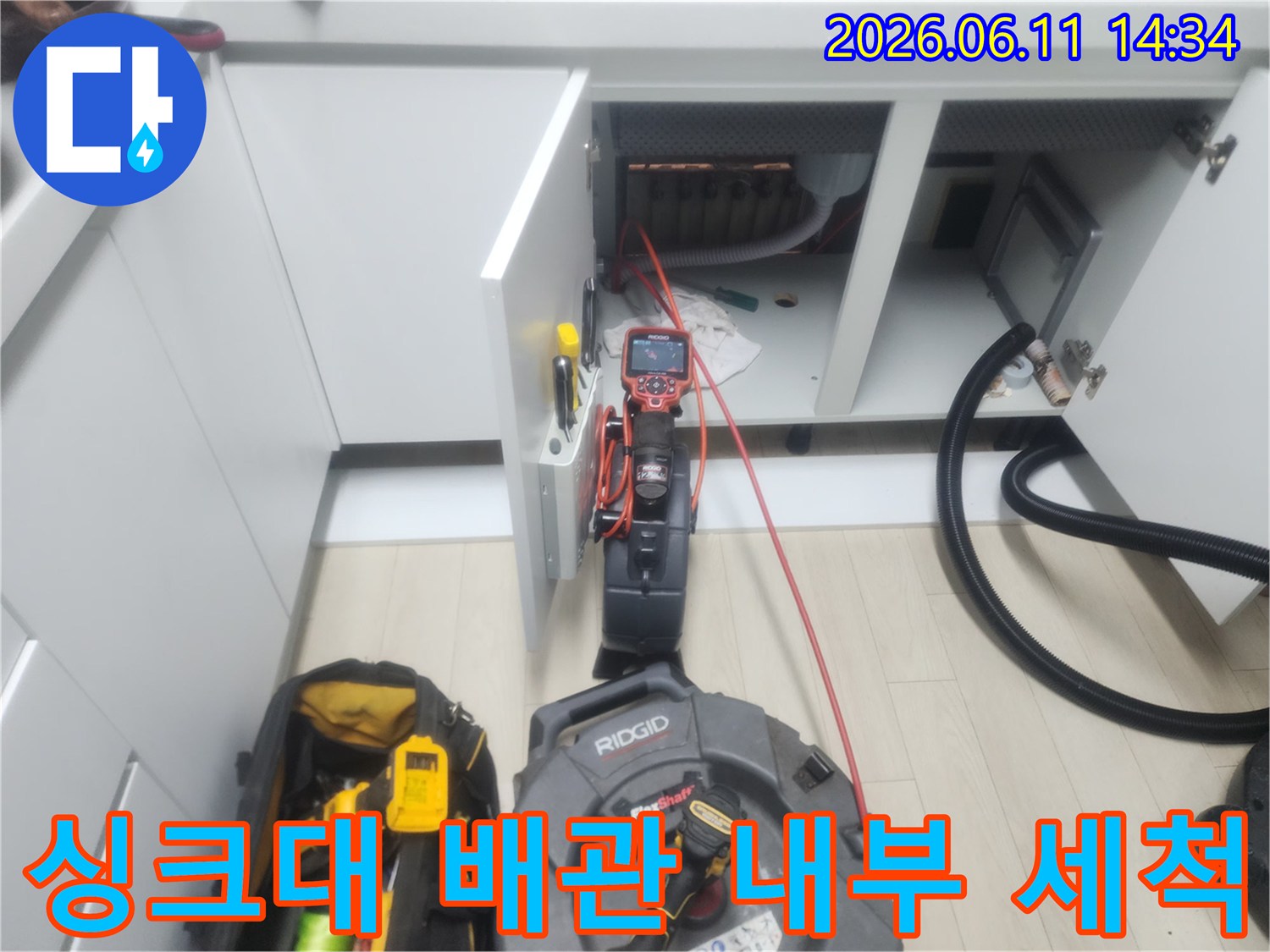 싱크대 하부장 공간에서 진행되는 배관 이물질 제거 작업 장면