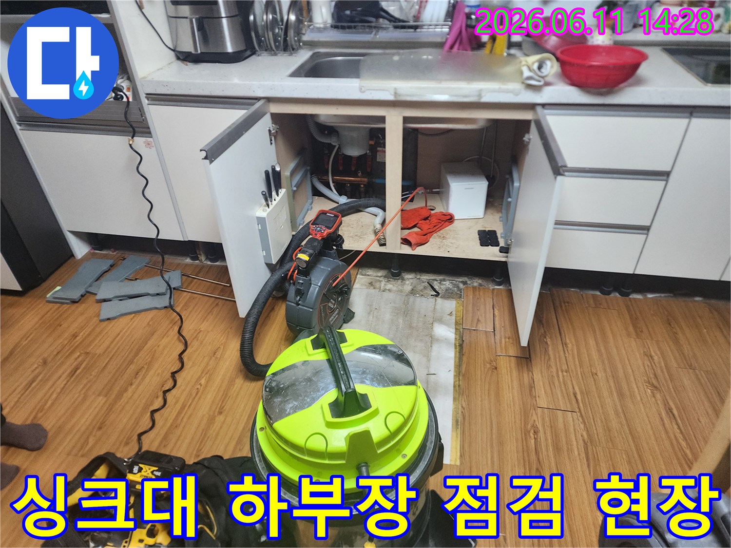 열려있는 싱크대 하부장과 배관 작업을 위해 배치된 장비들