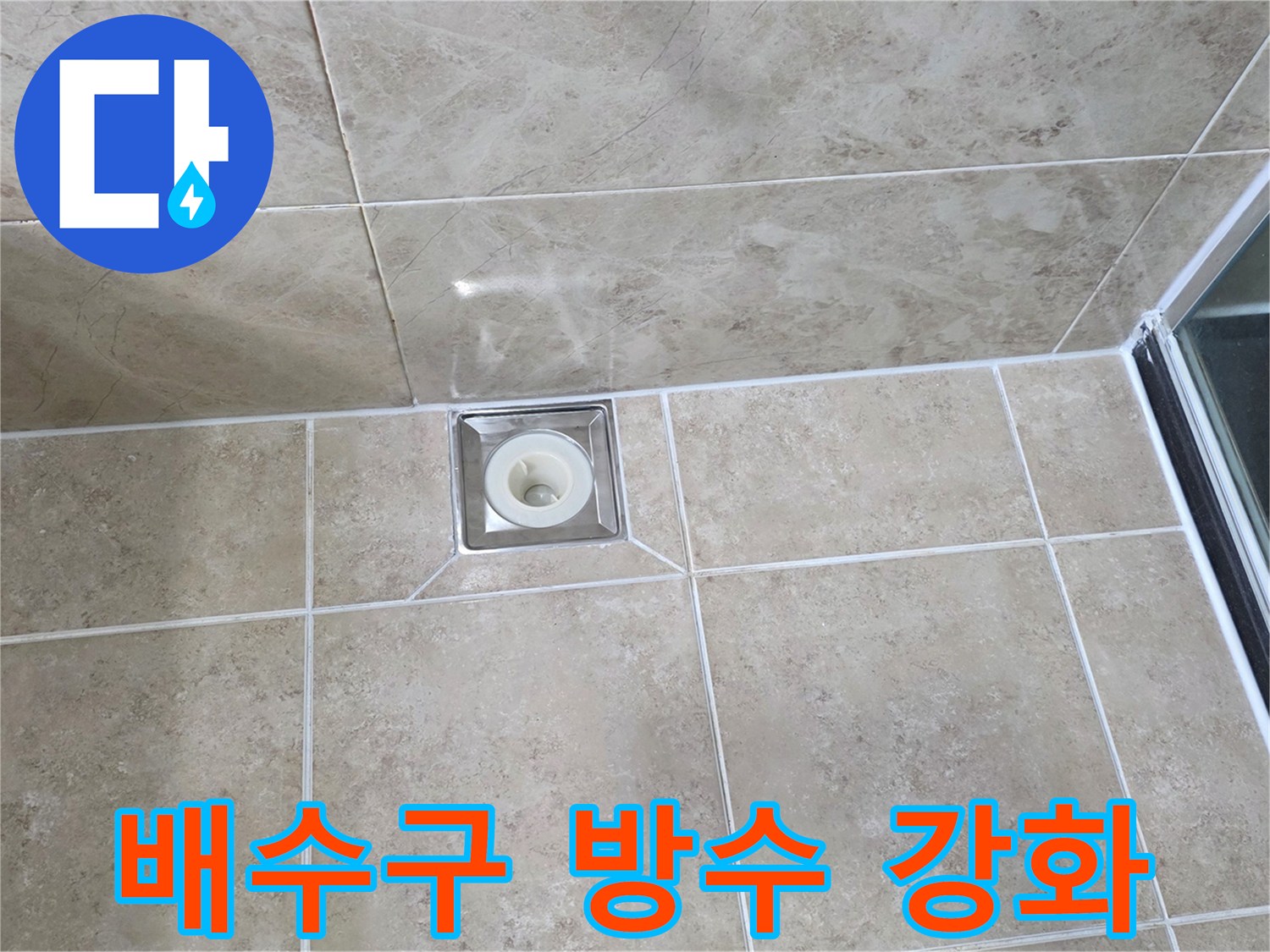 욕실 바닥에 설치된-사각형 스테인리스 배수구-주변 타일과 백시멘트 마감 상태를 보여주는 이미지입니다