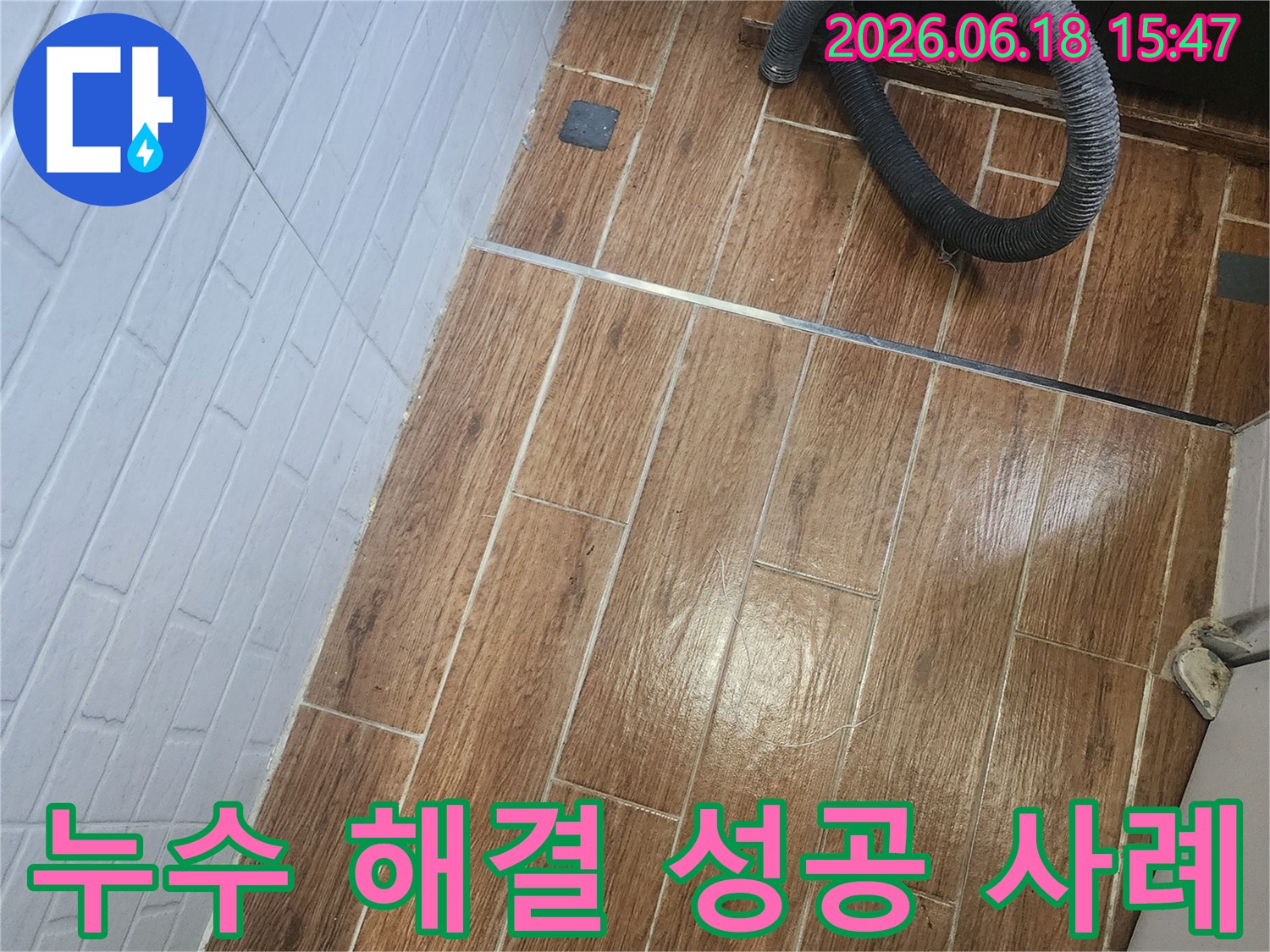 염창동 아파트에서 누수 해결 성공 사례를 보여주기 위한 탐지 및 공사 현장 사진입니다-바닥 타일 위에 검은색 호스가 놓여 있습니다.