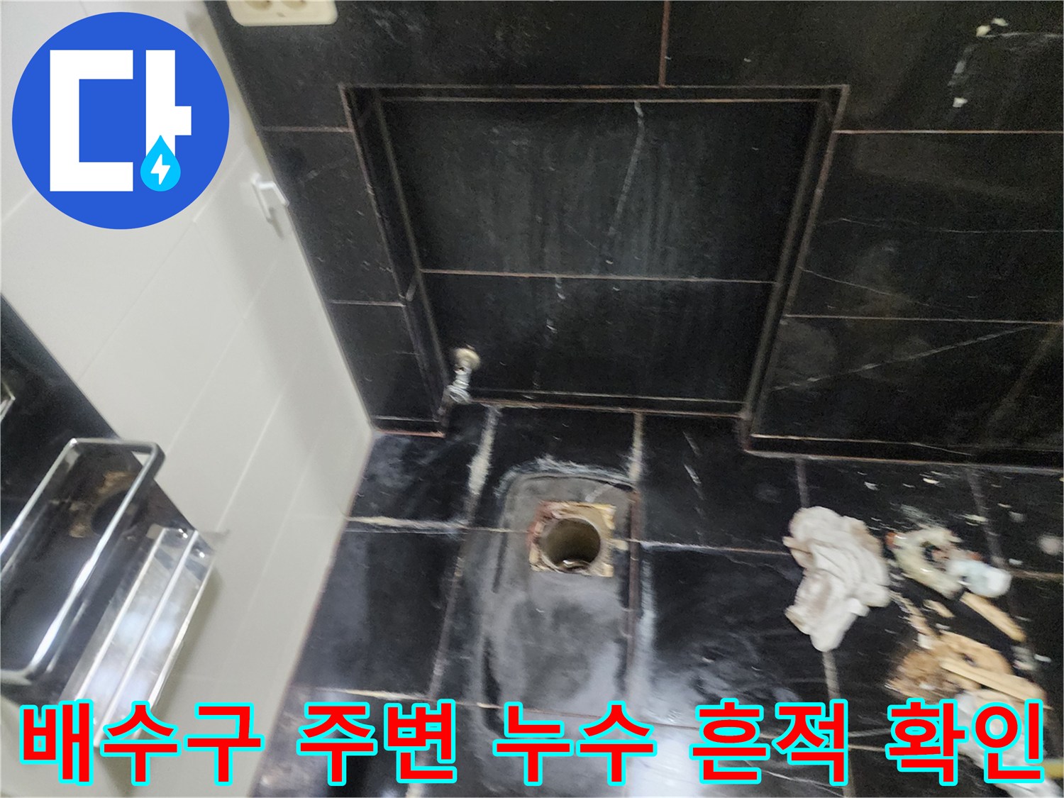 탈거된 변기 자리의 젖은 타일과 배관 입구