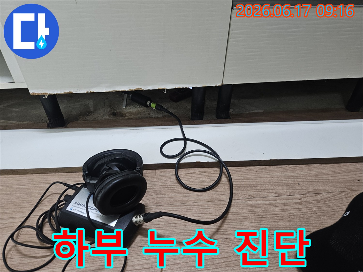 누수 탐지 장비의 센서가-싱크대 하부장 틈새에 삽입되어-누수음을 감지하며 진단하는 과정
