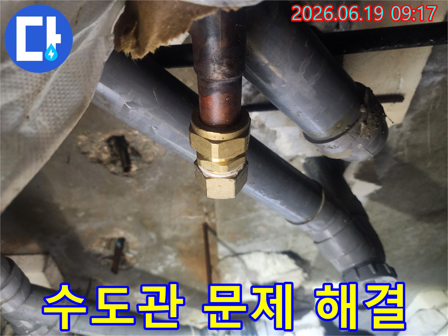 이 이미지는-천장 속-오래된 수도관의-연결 부위에서-발생한 누수를-새로운 황동 부품으로-교체하여-해결하는-전문적인-수리 현장입니다.