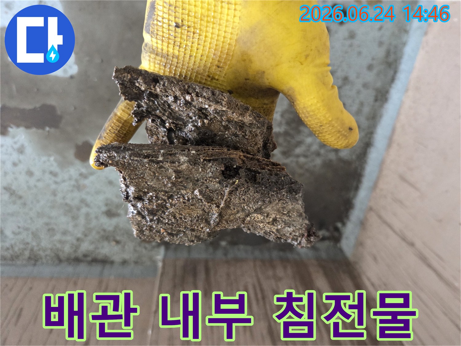 배관-공사-도중-발견된-오래된-배관의-부식된-잔해물을-노란-장갑을-낀-손으로-들고-있는-모습입니다.