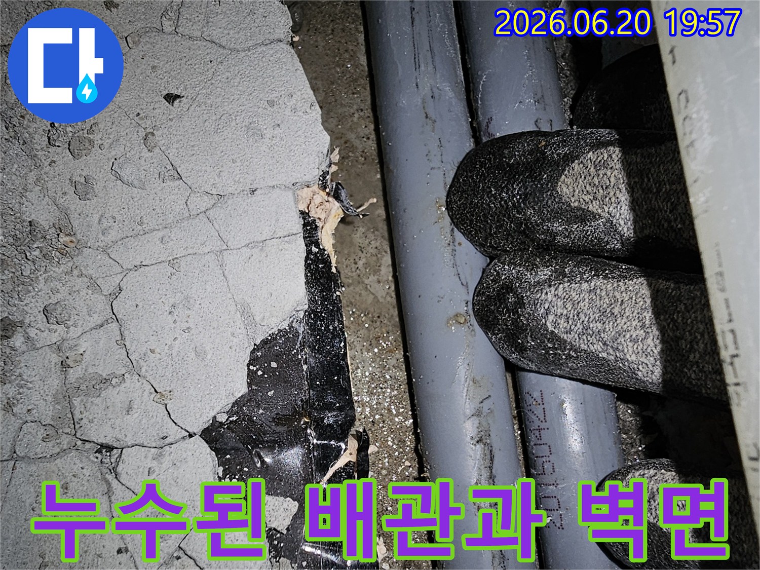 균열이 발생한 콘크리트 벽면과-노출된 배관 주변의-누수 현장을 보여줍니다