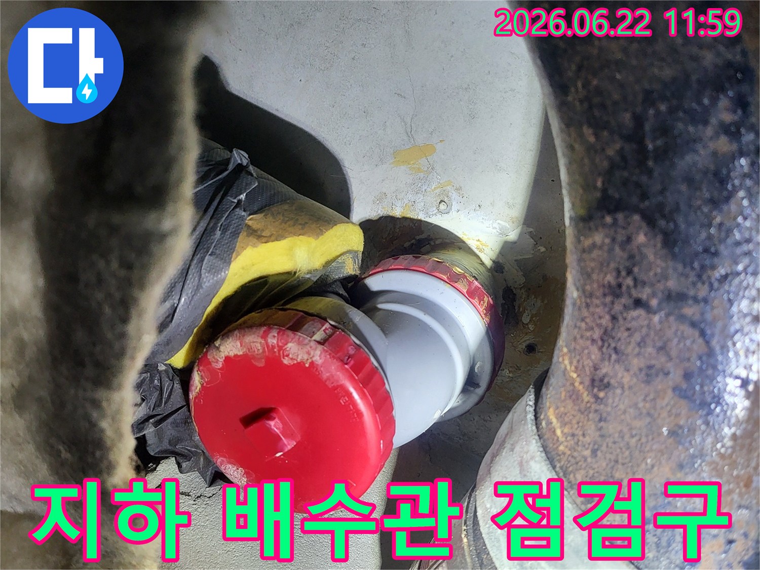 지하 배수관에-설치된 점검구와-주변 배관의-보온 처리 과정을-보여주는 현장 사진입니다