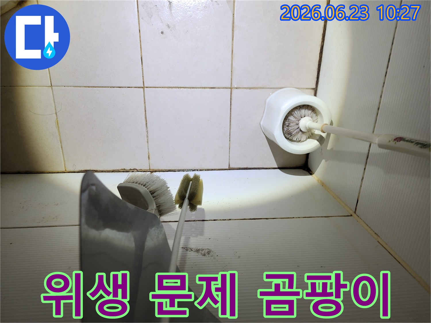 이 이미지는-욕실 바닥 타일의-줄눈에 생긴-검은 곰팡이와-오염된 청소용품-주변을-보여주며-위생 문제와-누수 가능성을-시사합니다.