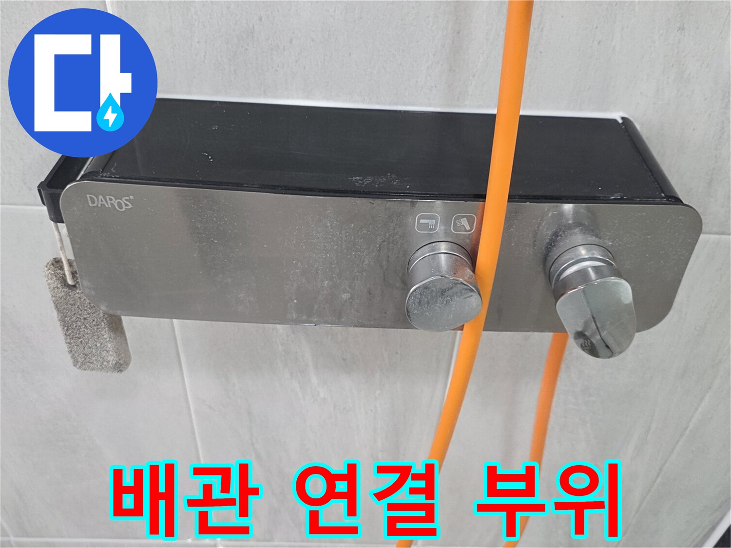 스테인리스 소재의 수전과 연결된 주황색 배관 호스