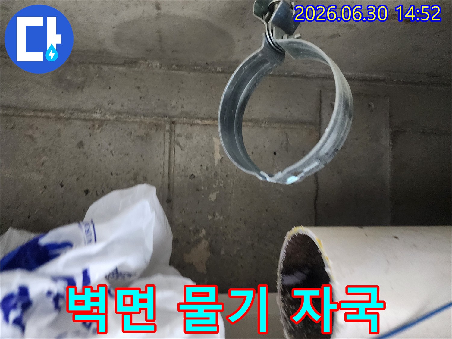 콘크리트 벽면에 선명하게 보이는-물기 자국과-배관 고정 밴드의-누수 현장 사진