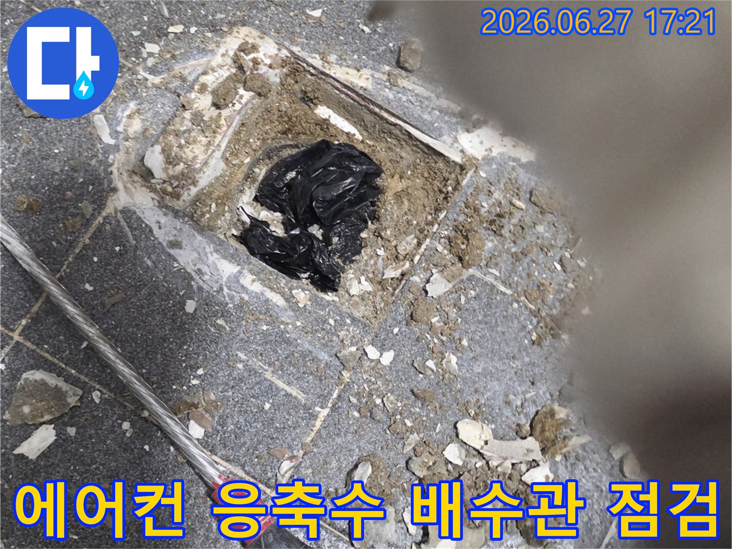 이 이미지는-에어컨 실내기에서 발생한 응축수 누수를 해결하기 위해-배수관의 막힘 여부를 점검하고-청소하는 작업 현장입니다.