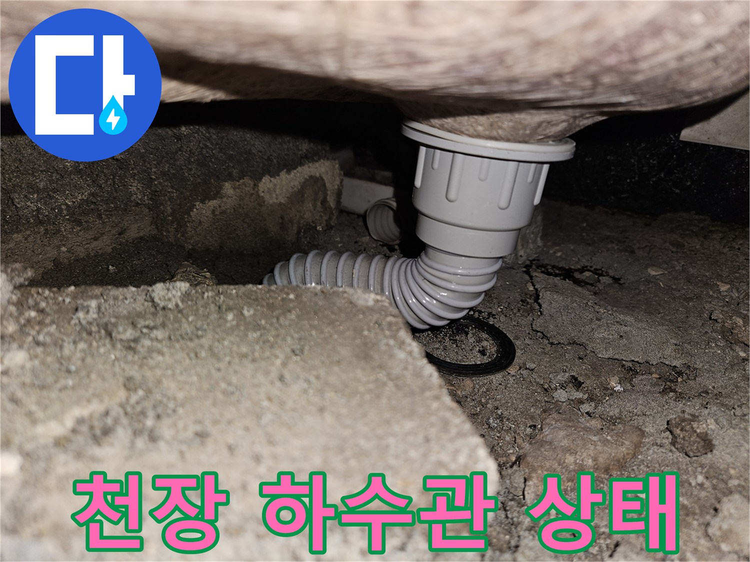 거친 콘크리트 천장 아래로 내려온 흰색 배관 부속