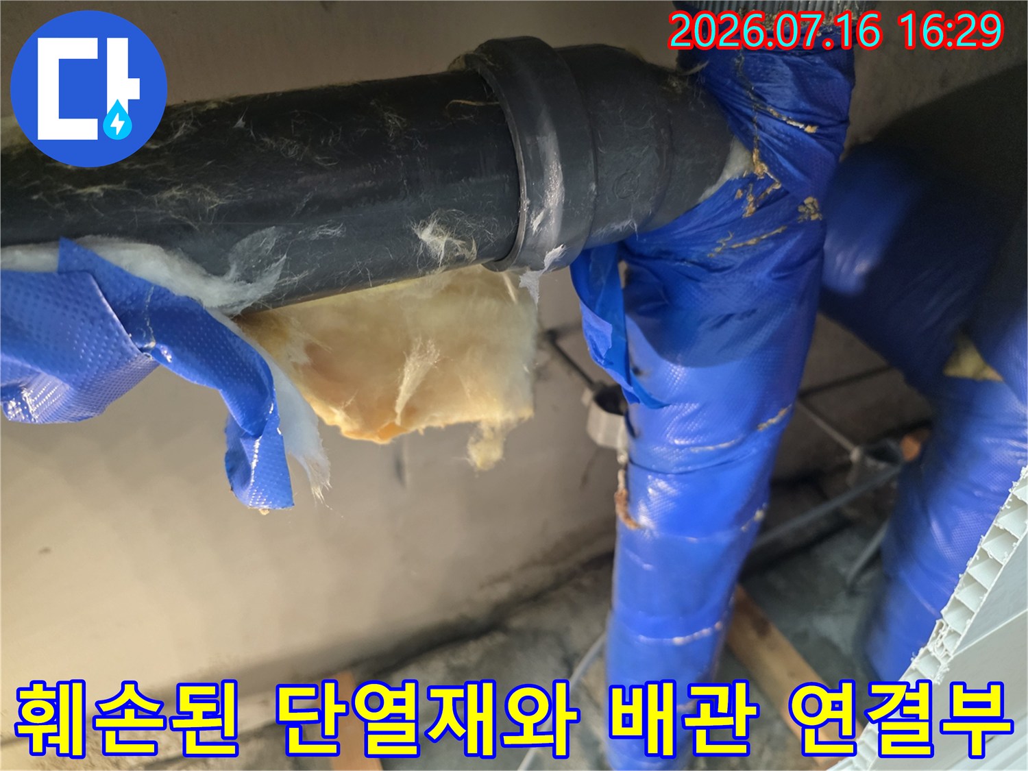 장갑을 낀 손으로 파손된 천장 내 배관 부위를 가리키는 사진