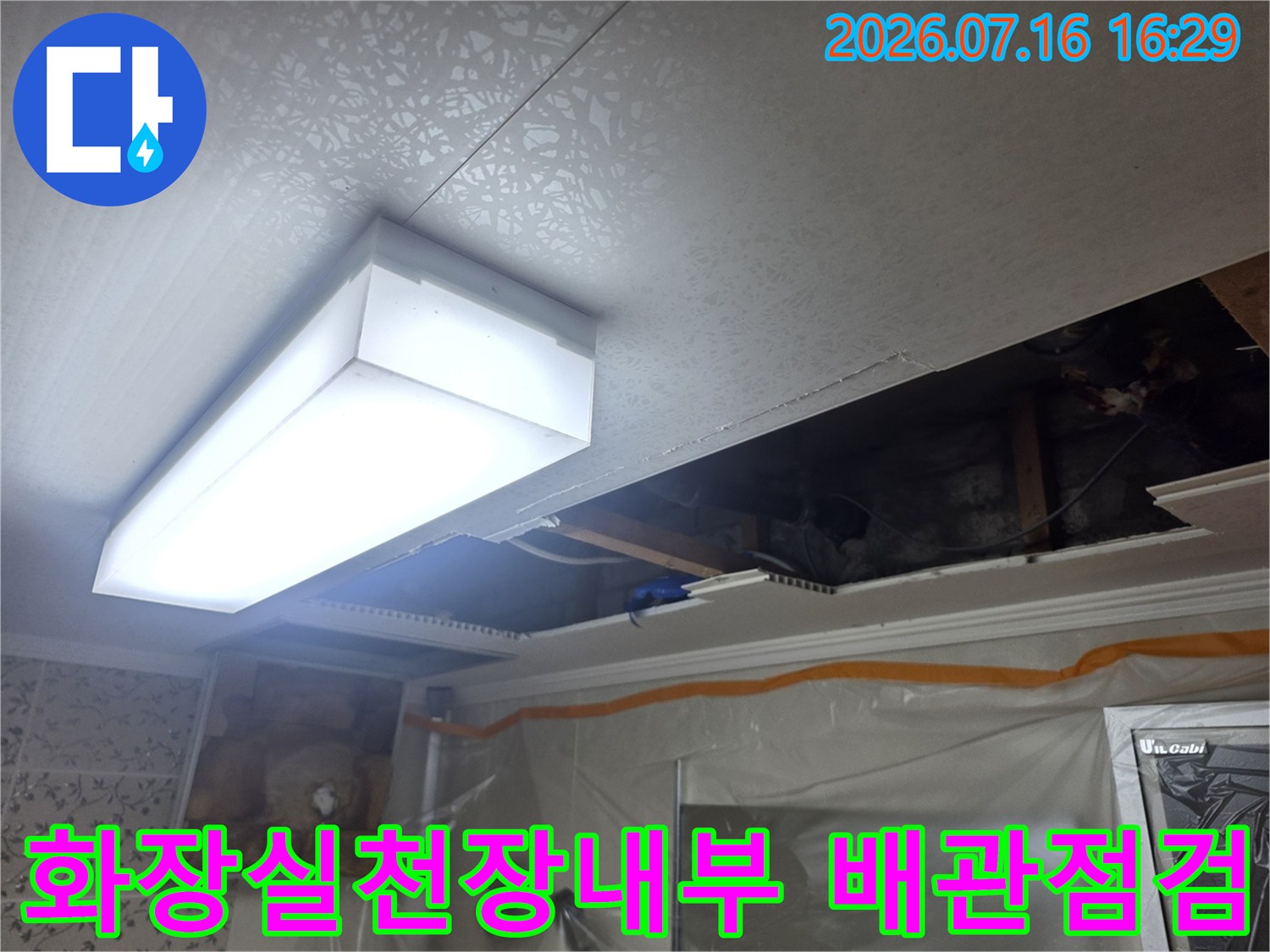 화장실 천장 내부의 노출된 배관과 전등이 보이는 점검 구역 모습