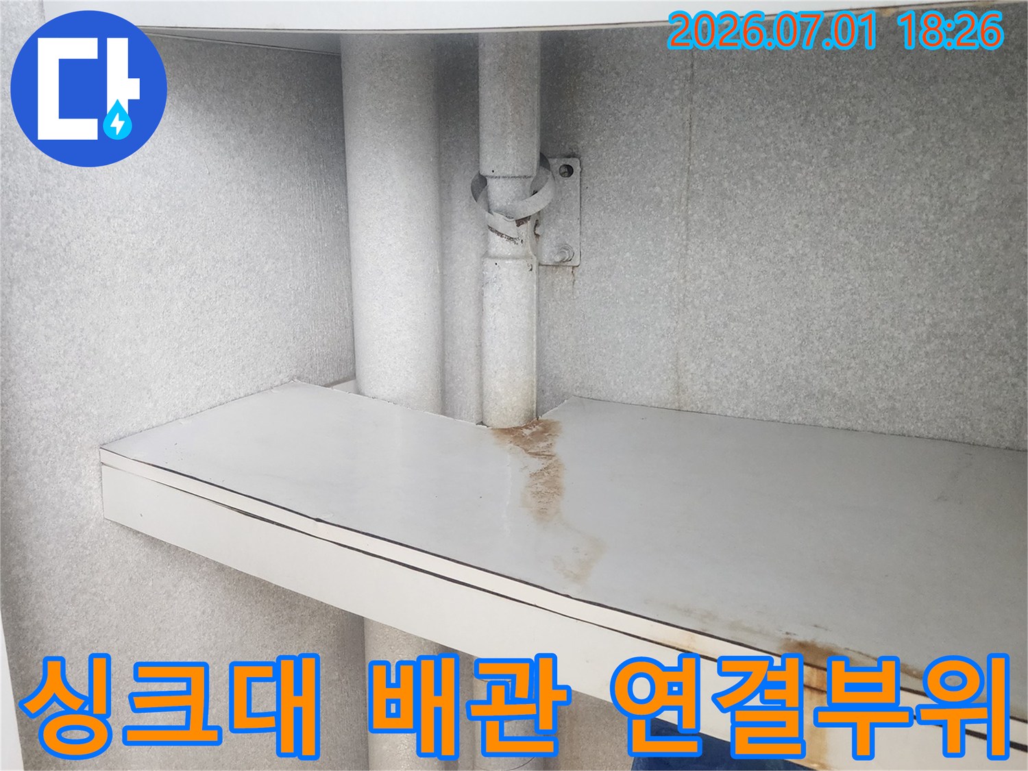 이 이미지는-싱크대 하부-배관의 연결 부위에서-발생한 누수로 인해-주변 가구 패널에-생긴-물 자국을-보여줍니다