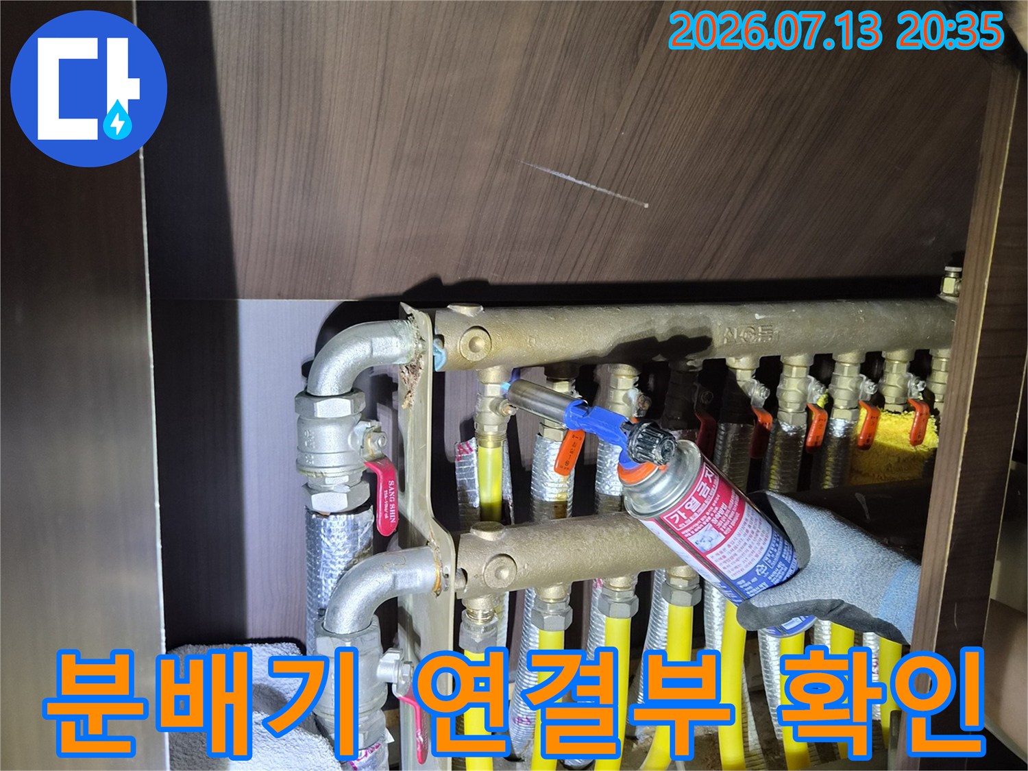 보온재가 씌워진 난방 배관들과 금속제 분배기의 결합부 점검 장면