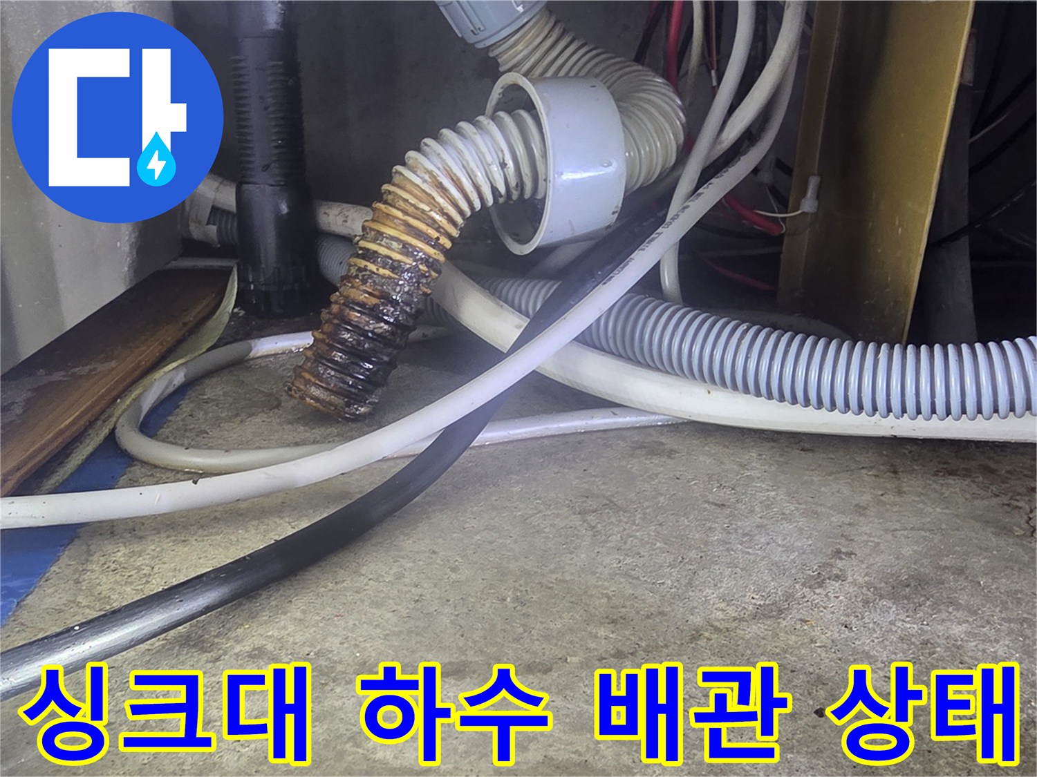 싱크대 아래쪽의 굴곡진 하수 배관과 연결된 호스들