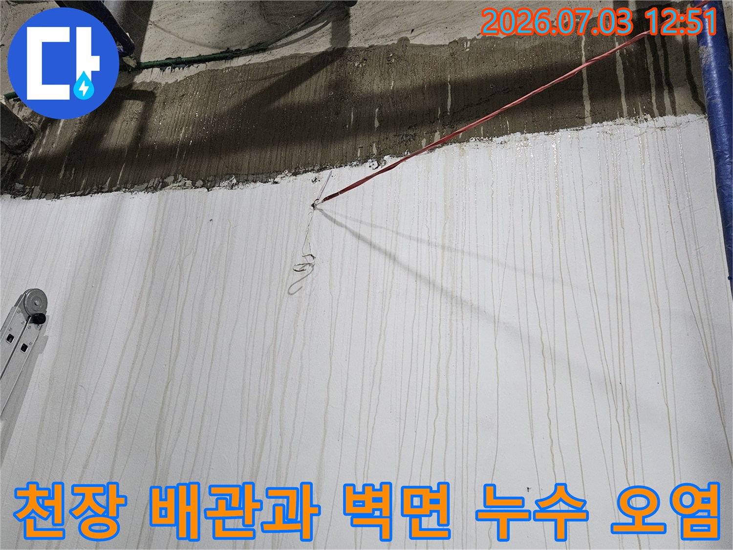 상단 콘크리트 턱 아래로 물이 흘러내려 벽면이 오염된 모습-작업용 사다리가 왼쪽에 배치됨