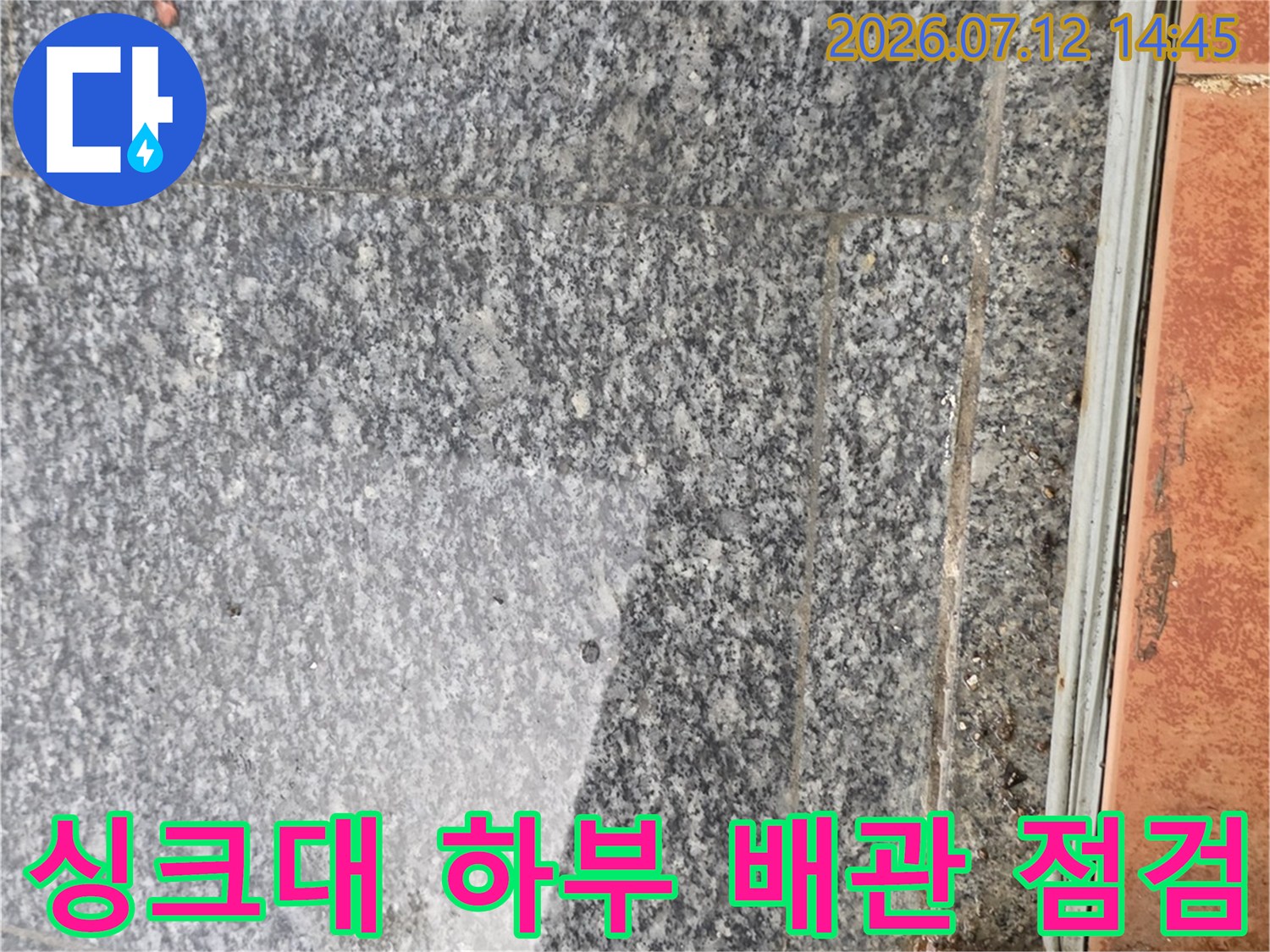 싱크대 아래쪽 그레이톤 석재 마감재와 배관 연결 부위를 점검하는 모습