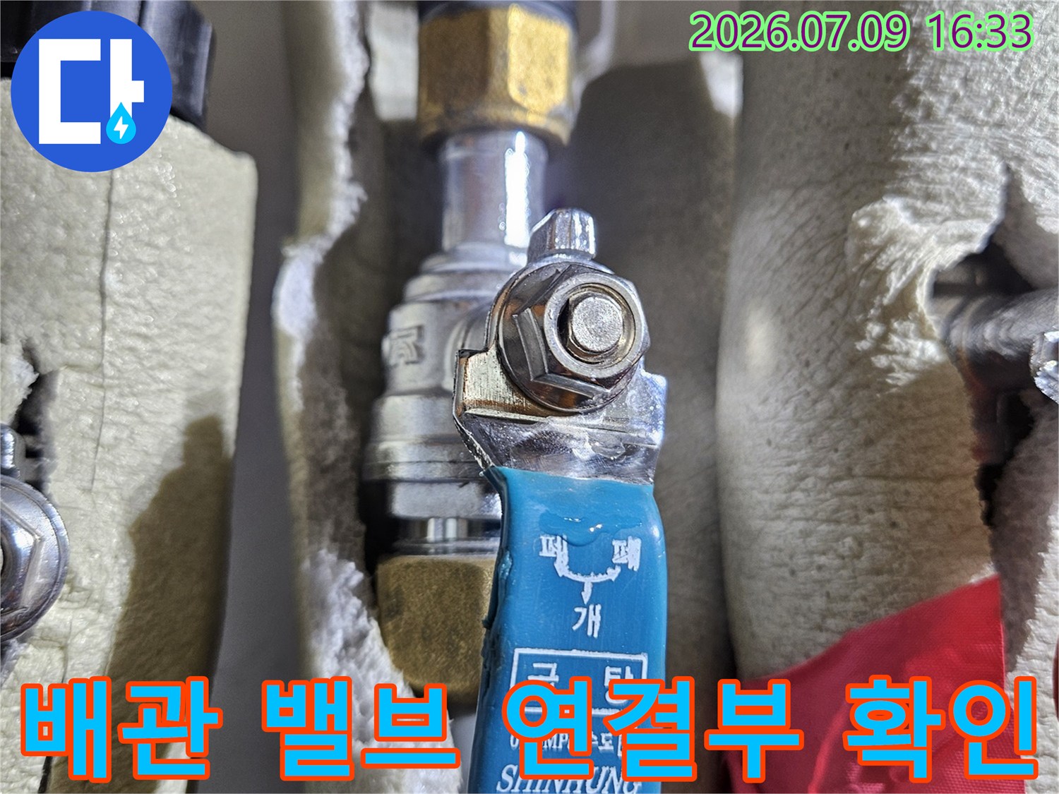 온수 배관이 노출된 곳에서 파란색 밸브와 황동 색상의 어댑터가 결합된 모습