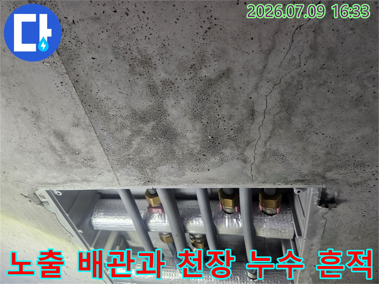 천장 콘크리트 표면의 습기 얼룩과 노출된 상부층 연결 배관