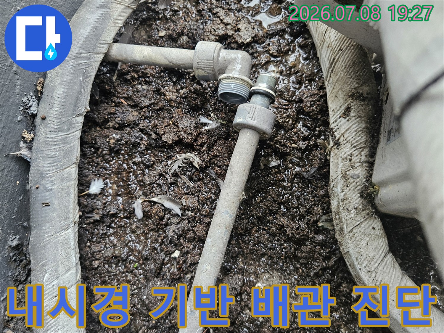 노출된 하부 배관의 상태와 주변 토양의 습기 여부를 촬영한 사진