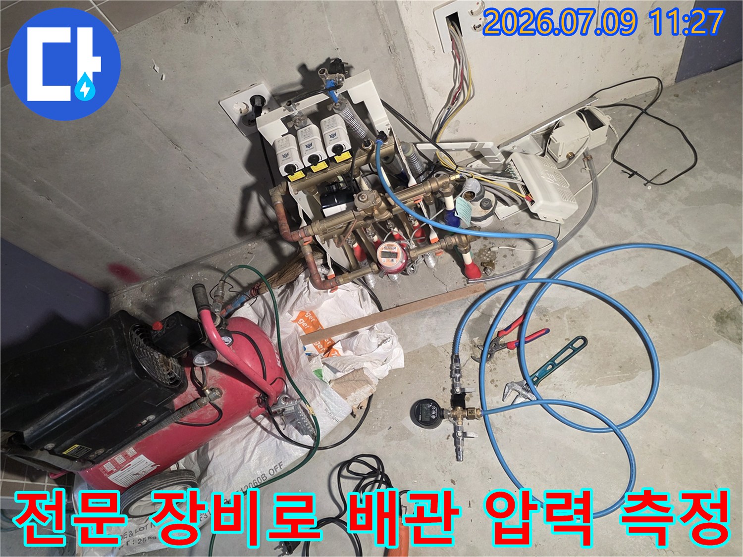 호스와 게이지를 연결하여 신설된 배관의 기밀 상태를 점검하는 현장 사진