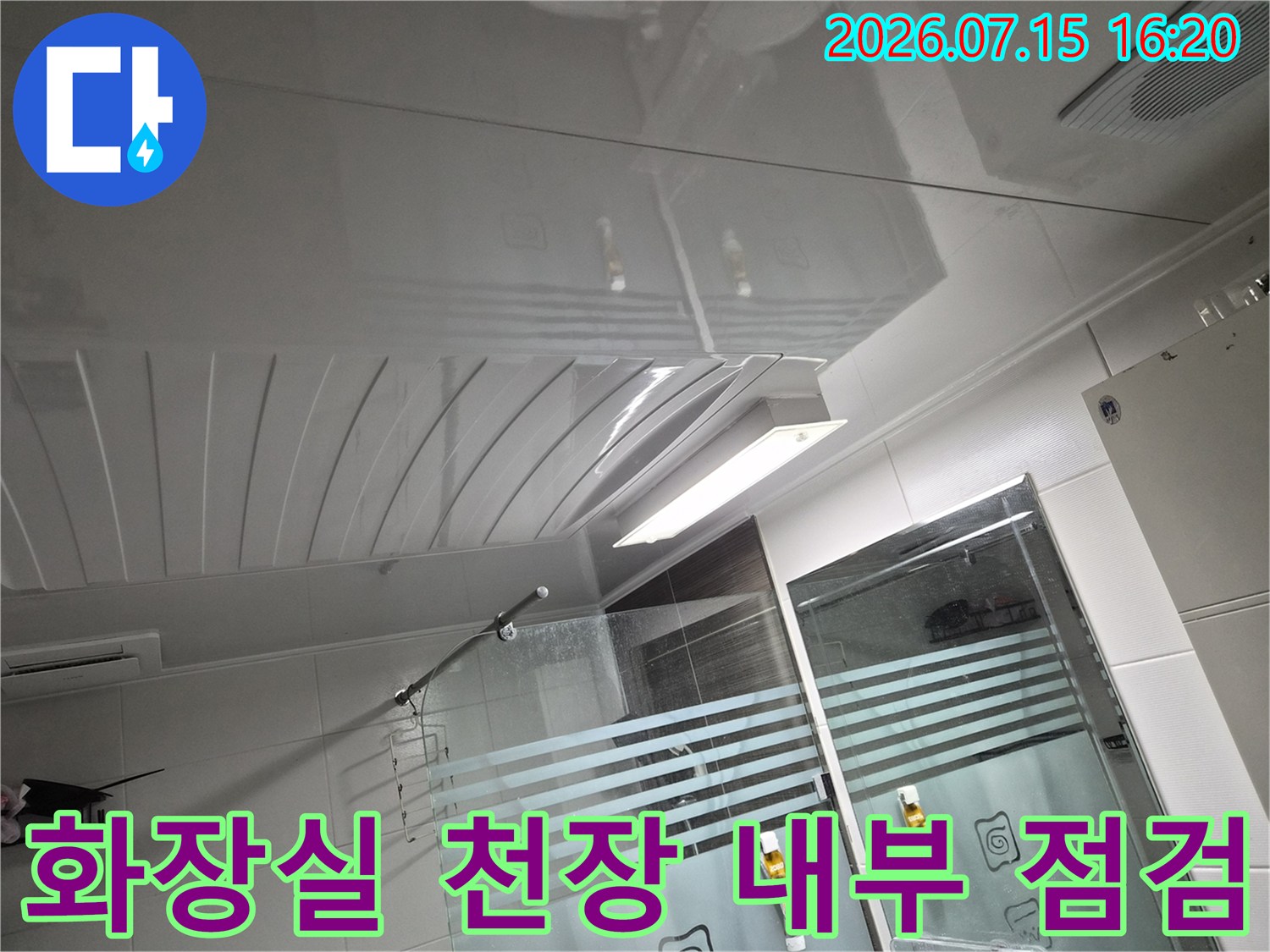 화장실 천장 마감재를 제거하고 노출된 배관과 조명 설비를 점검하는 모습