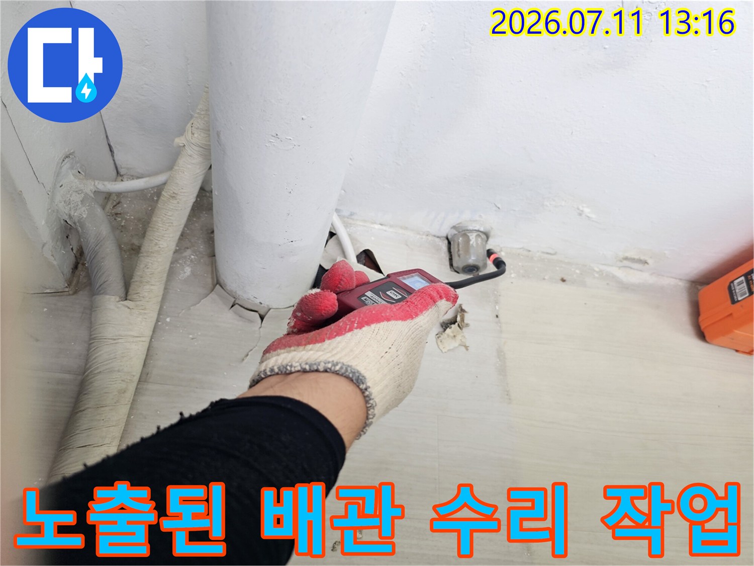 장갑을 낀 작업자가 렌치로 노출된 하수 배관 연결 부위를 정밀하게 점검하는 모습