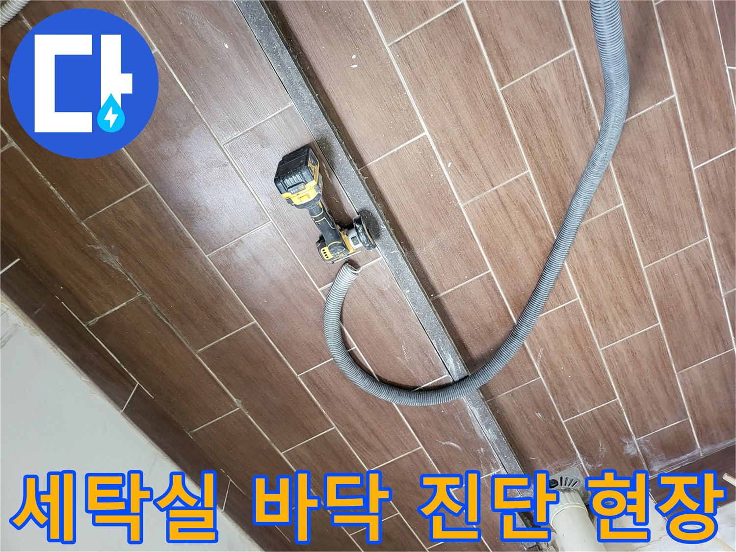 전동 드릴과 호스가 놓여 있는 세탁실 타일 작업 부위