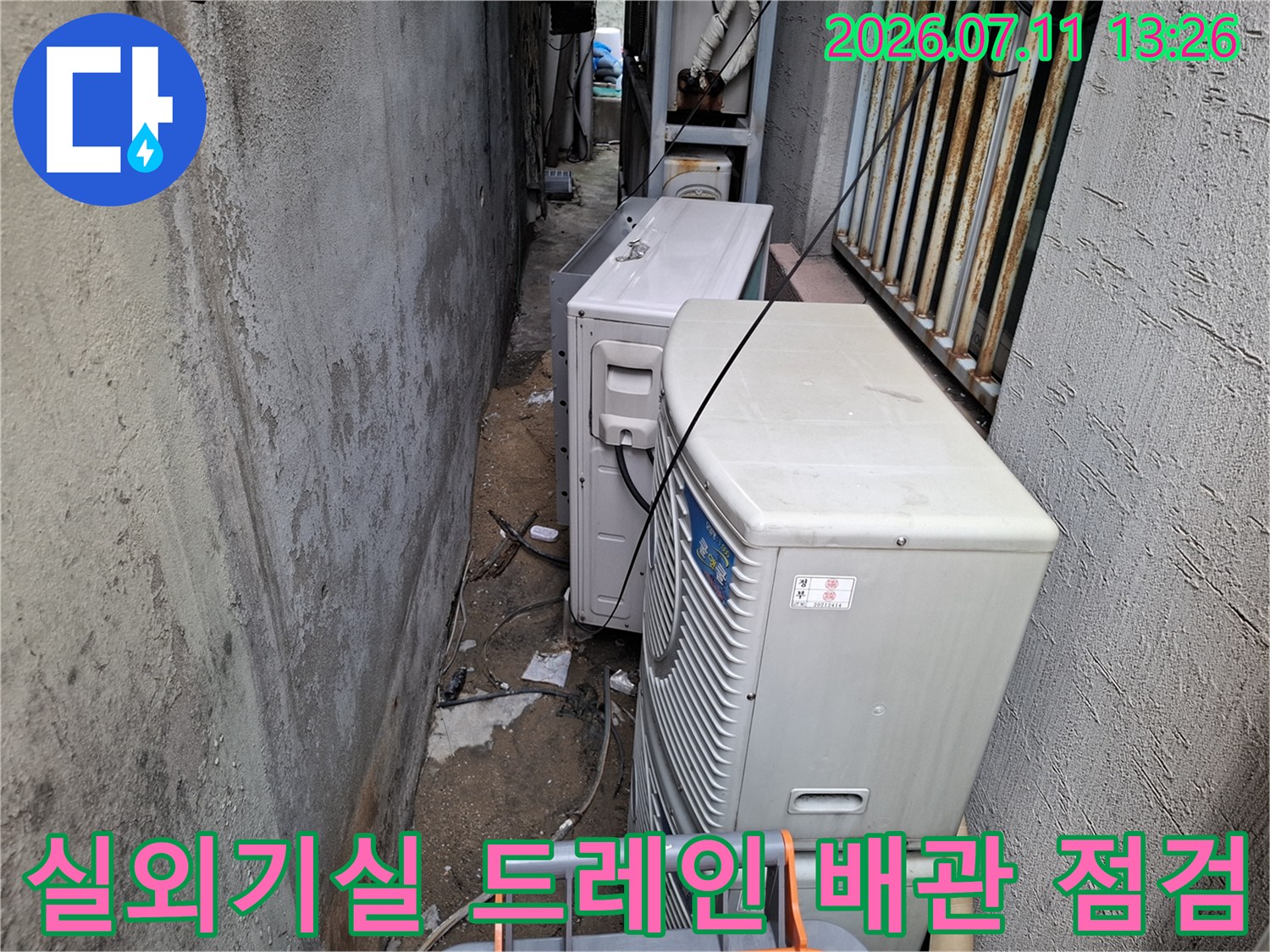 실외기들이 설치된 좁은 공간의 드레인 배수관 점검 모습