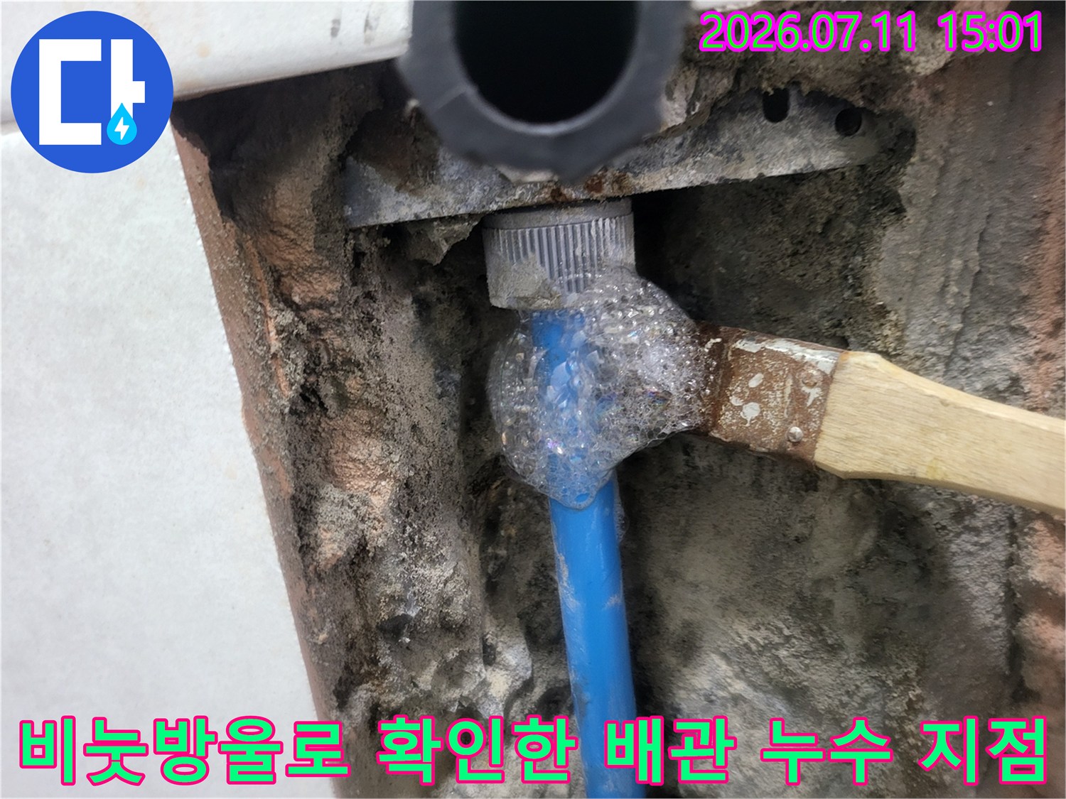화장실 벽면에 매립된 파란색 배관 연결 부위에서 기포가 발생하는 순간의 사진