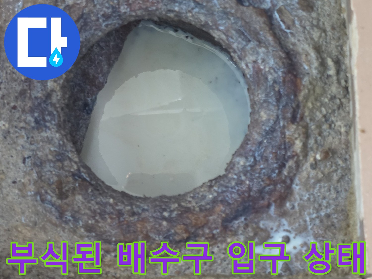 세탁실 하수구 주변의 부식된 배관과 젖은 타일 모습