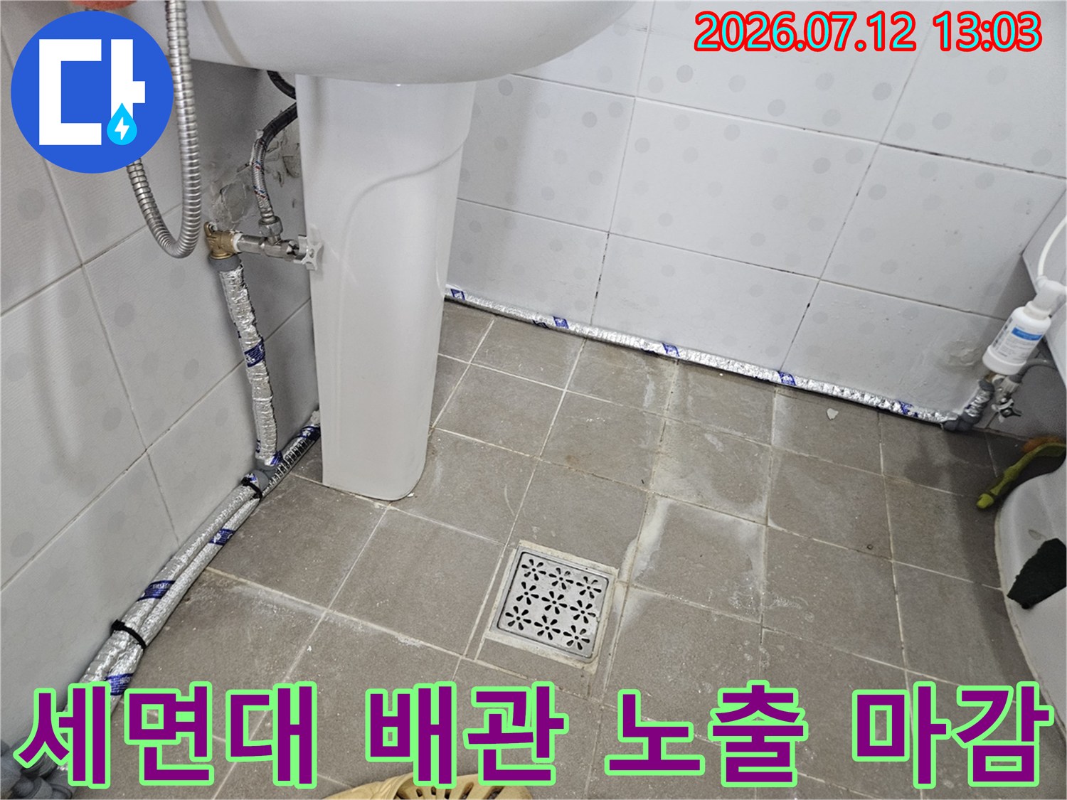보온재로 감싸진 화장실 세면대용 직수 배관과 배수구 근처 모습
