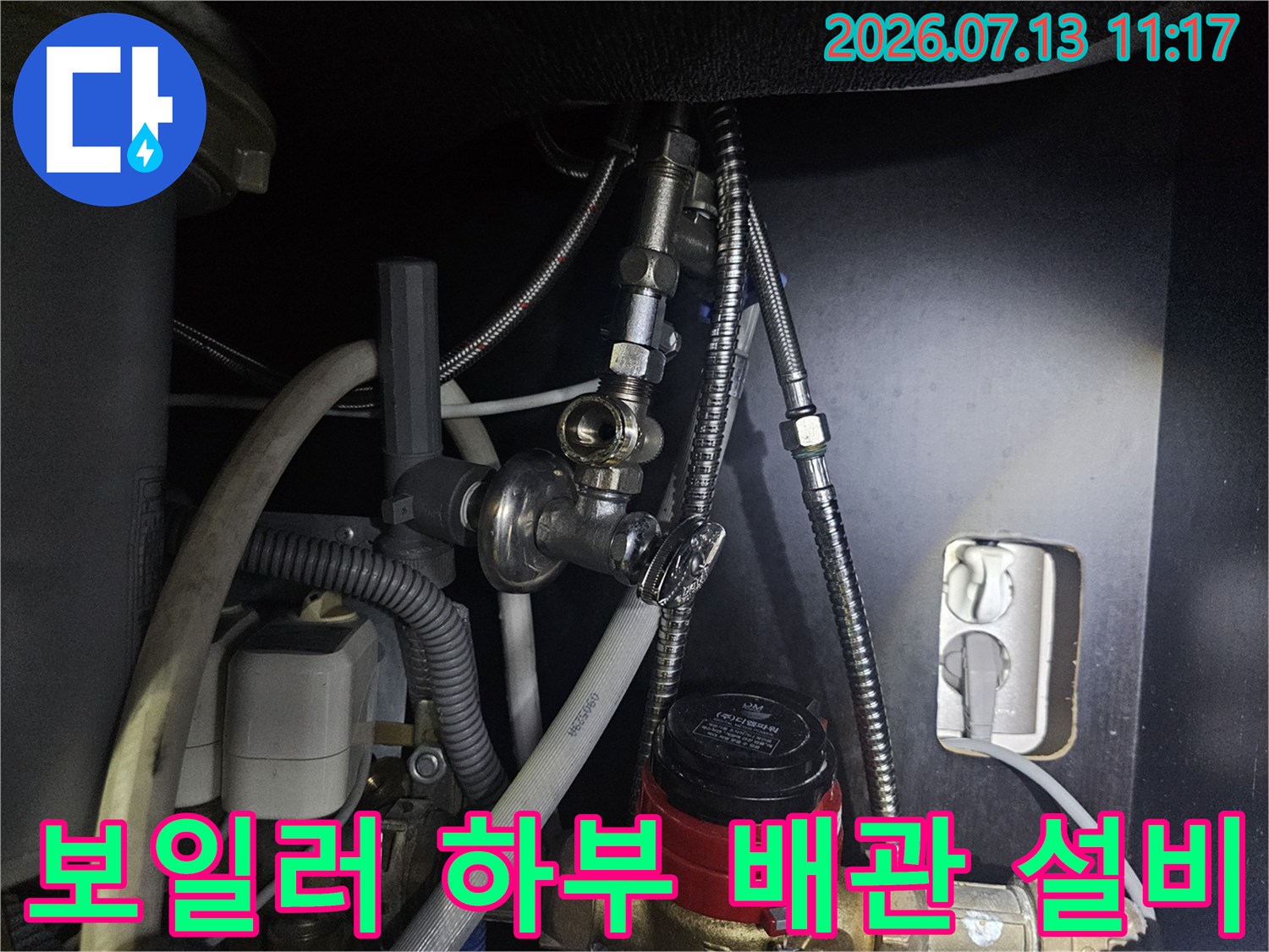 다양한 금속 배관과 빨간색 핸들 밸브가 복합적으로 연결된 구조-사진