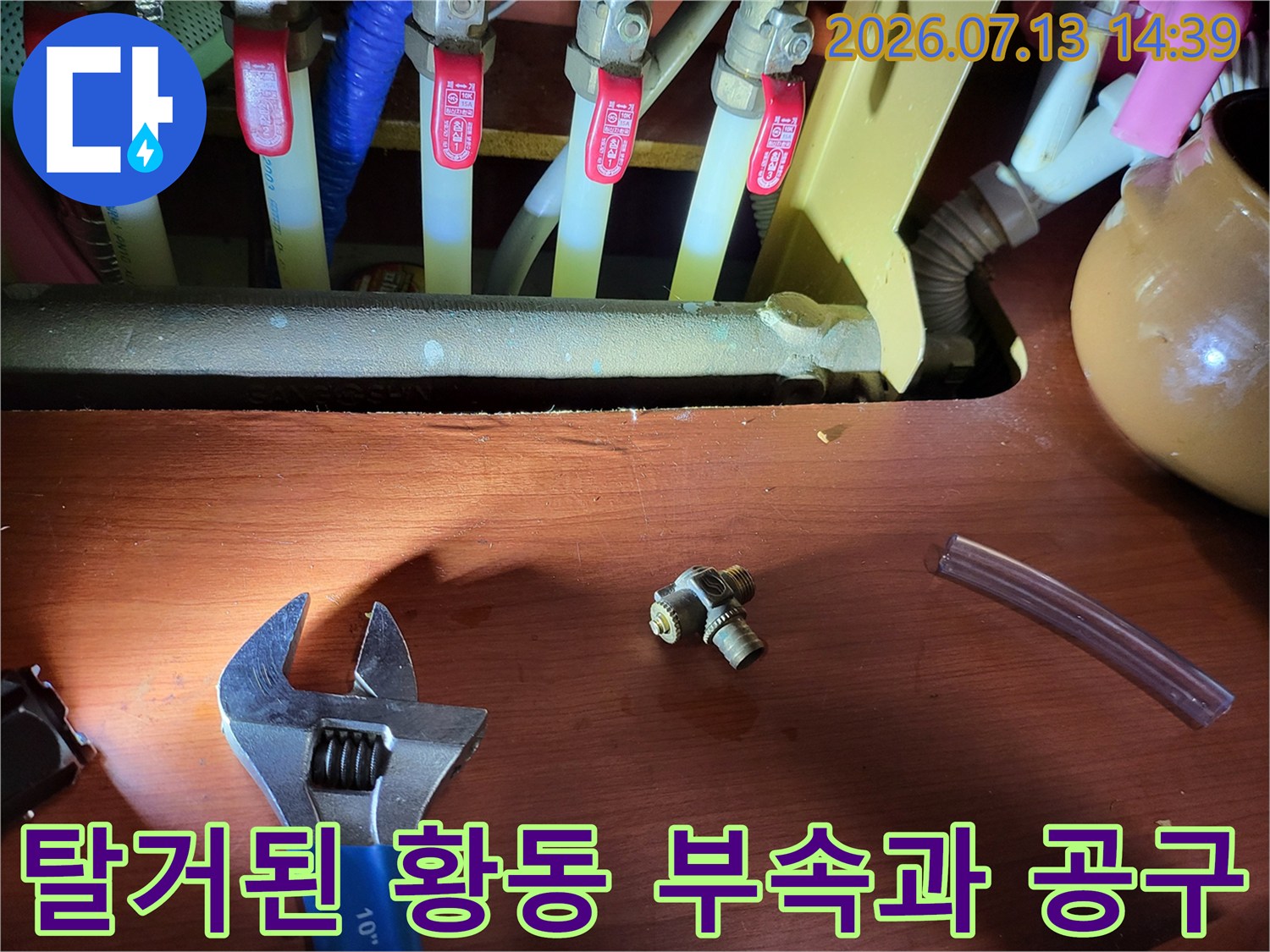 분배기 하단에서 분리해낸 금속제 티-어댑터와 작업용 렌치가 놓인 장면