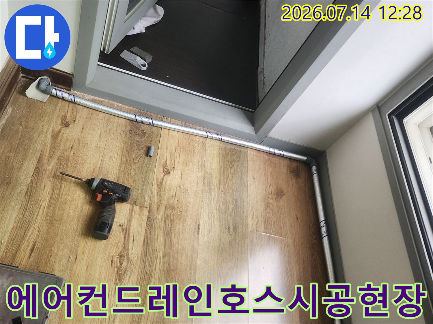 베란다 바닥재 위에 설치된 에어컨 배수 호스와 작업 장비