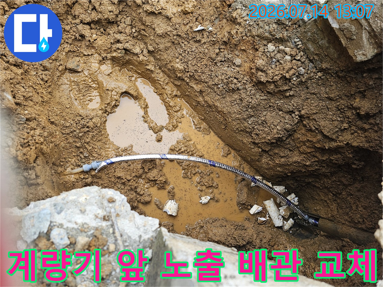 노출된 파란색 계량기 연결 배관과 젖은 토사 지면의 모습