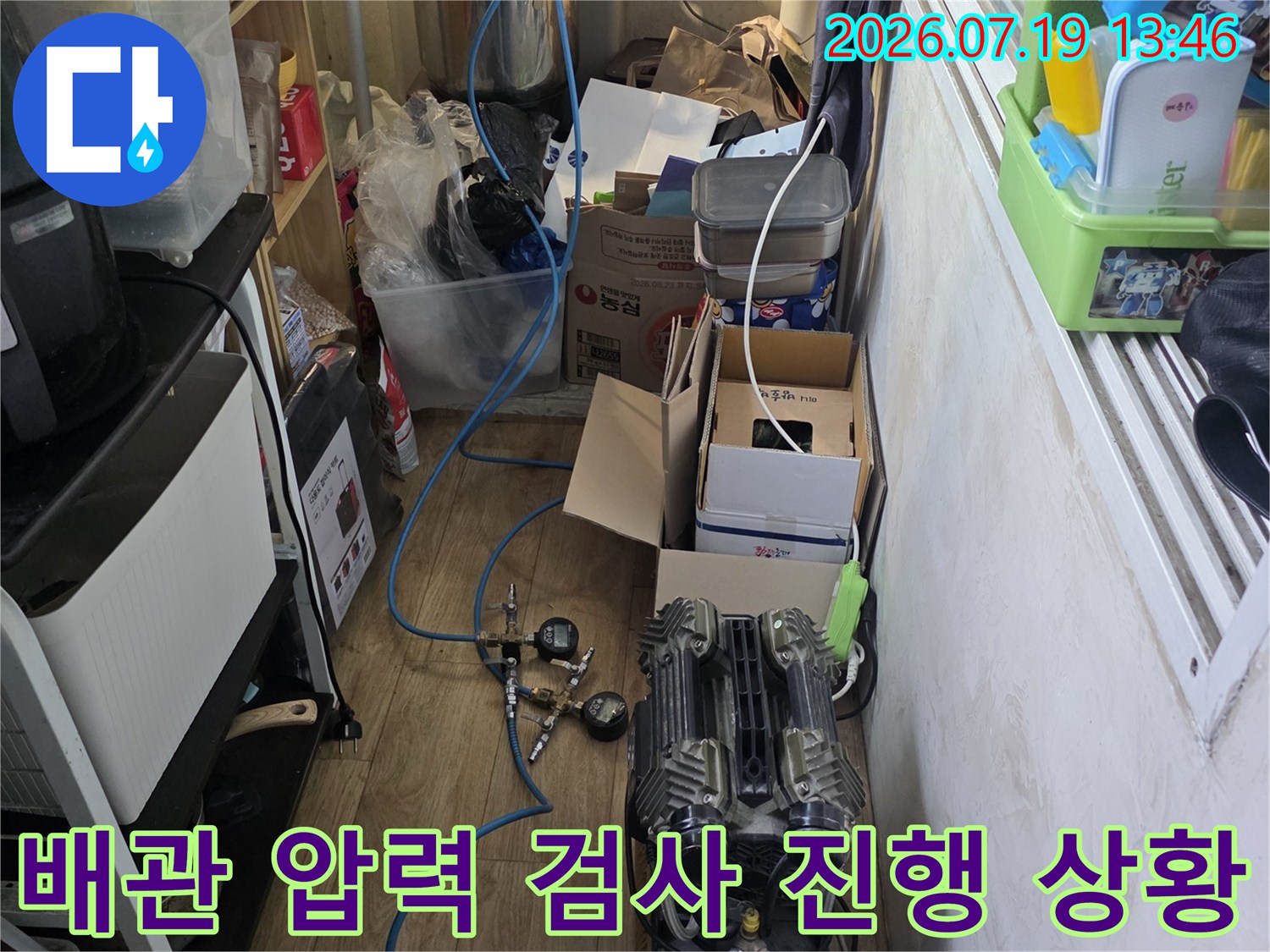 파란색 배관 호스가 연결된 전문 누수 탐지 장비가 바닥에 놓여 있는 모습