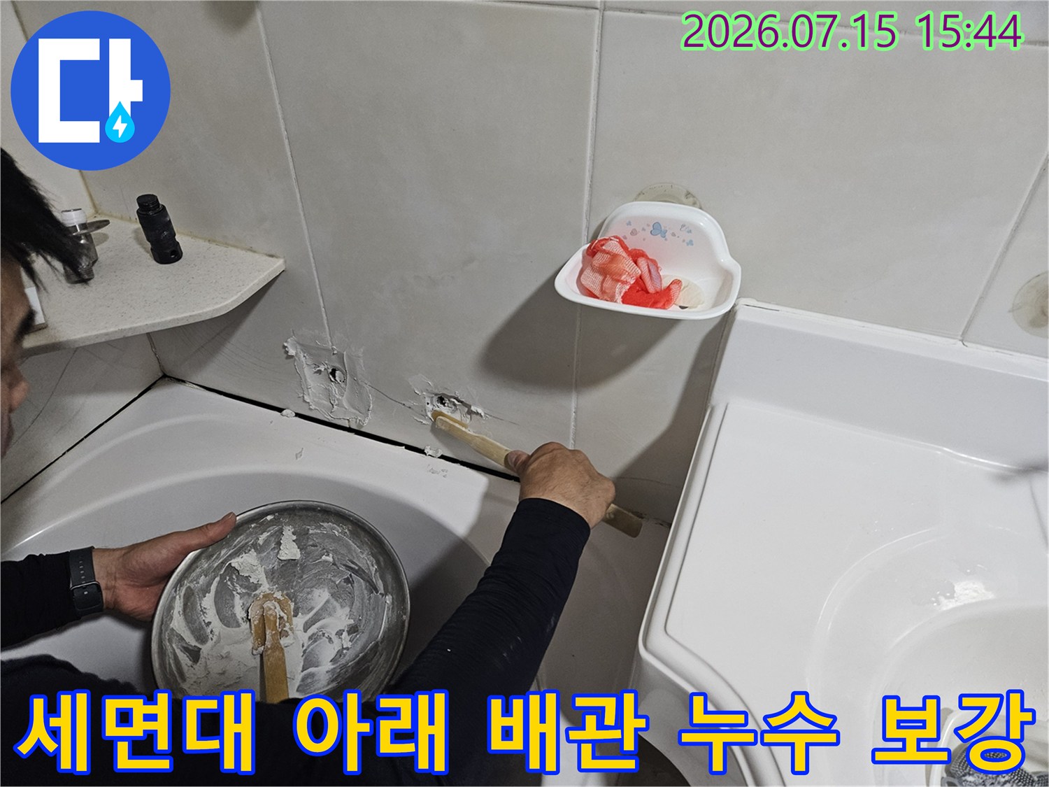 기술자가 세면대 하단 노후 배관을 새 부속으로 교체하는 전문 작업.