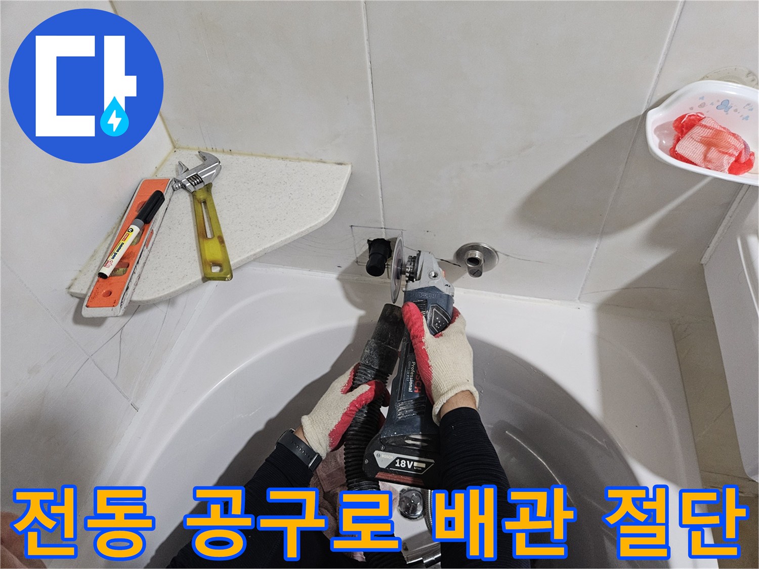 배관 보수를 위해 전동 톱으로 관을 자르는 작업자 손