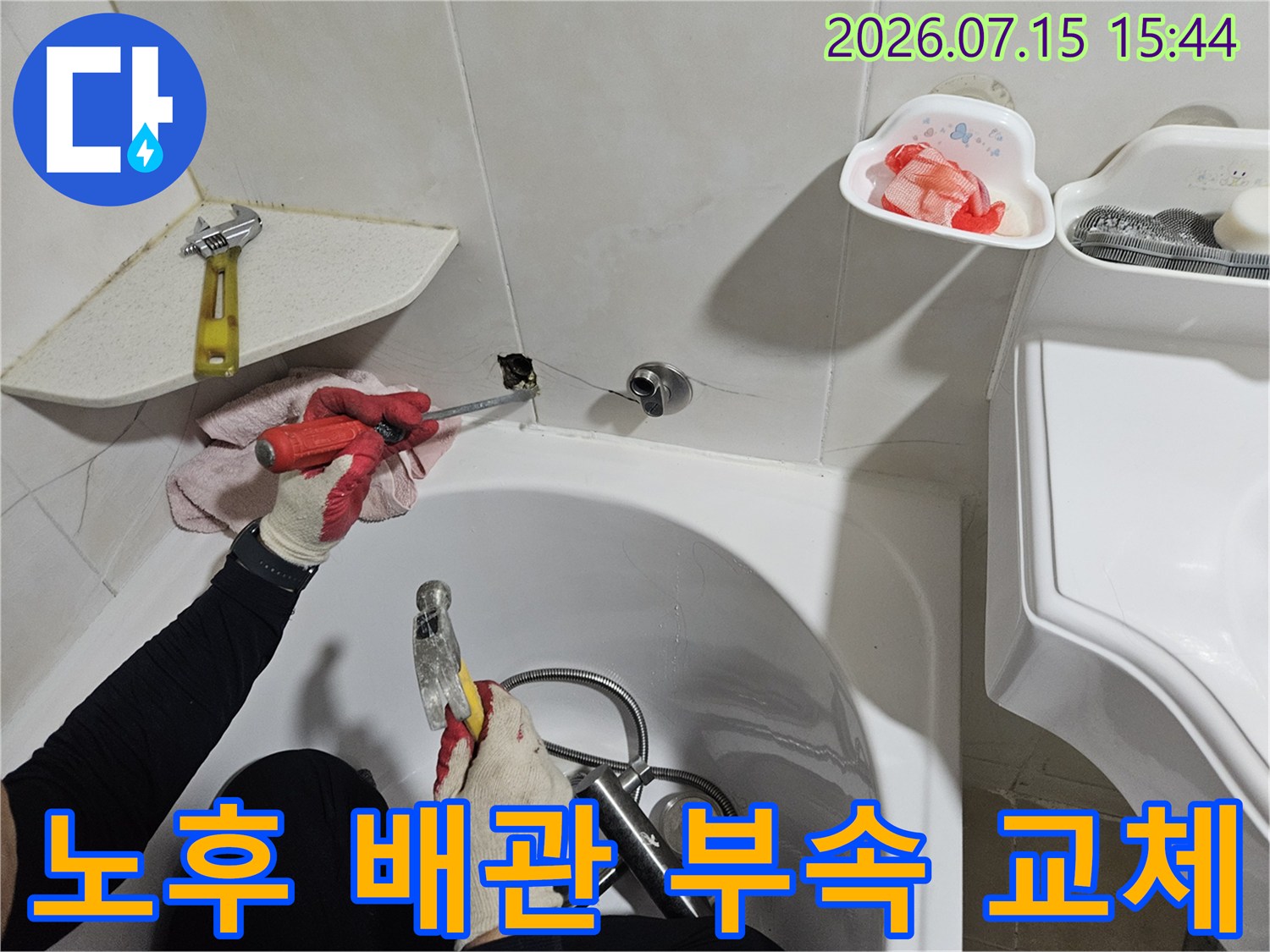 화장실 세면대 아래 노출된 배관의 결함 부분을 제거하고 새 파츠로 대체하는 장면