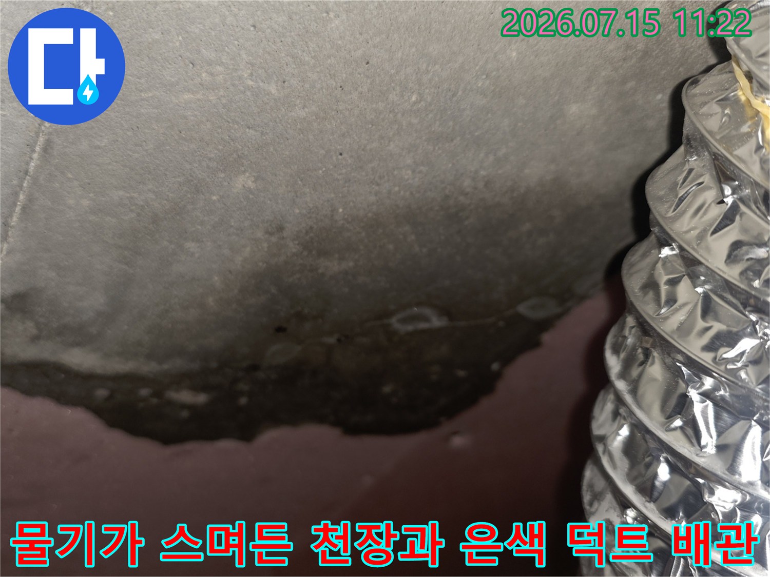 젖어서 어둡게 변한 천장 마감재-옆으로 나란히 배치된 주름진 형태의 은색 금속 배관