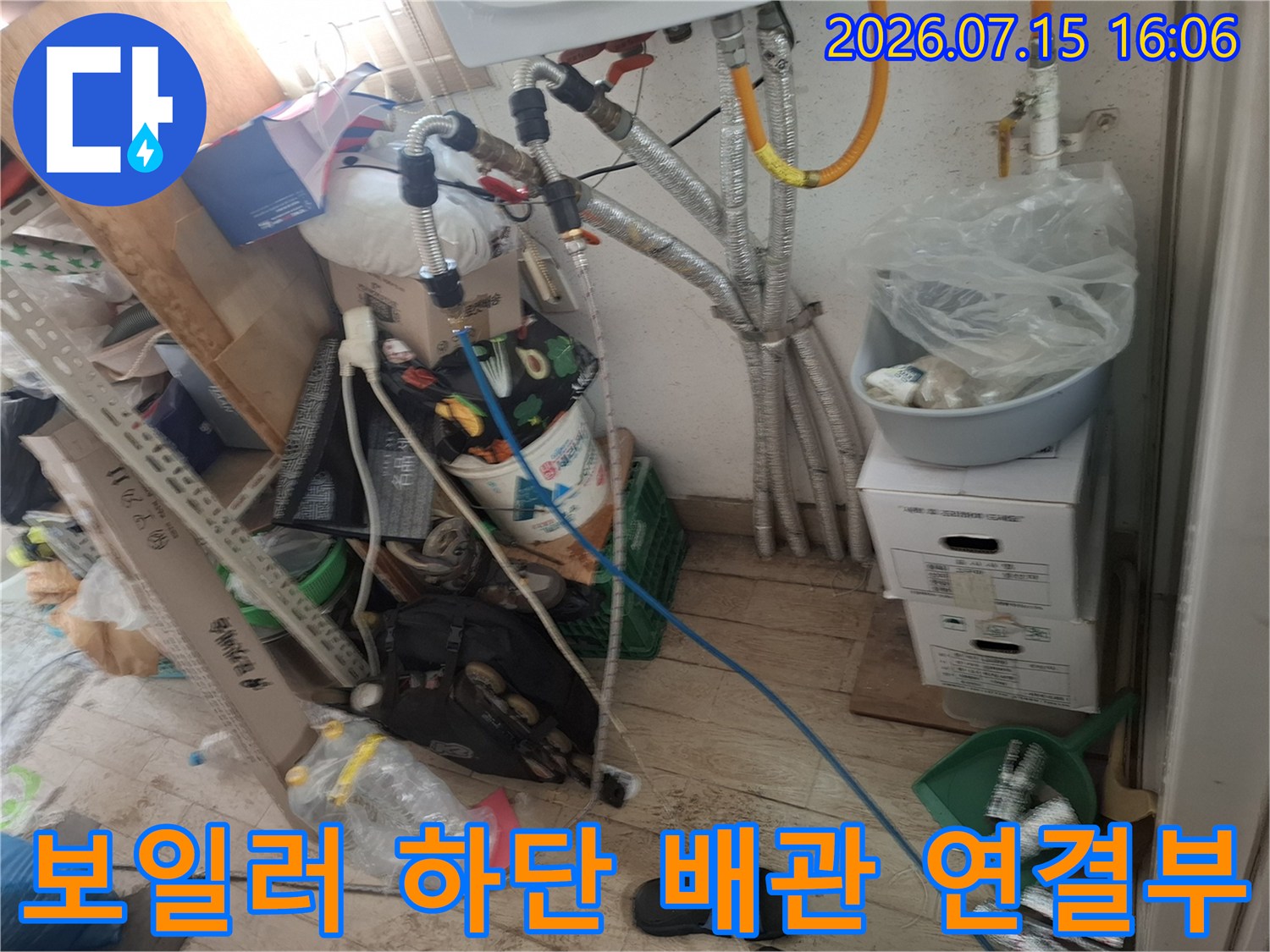 보일러 아래쪽으로 복잡하게 얽혀 있는 금속제 배관과 파란색 호스-연결 부위 상태 점검 모습