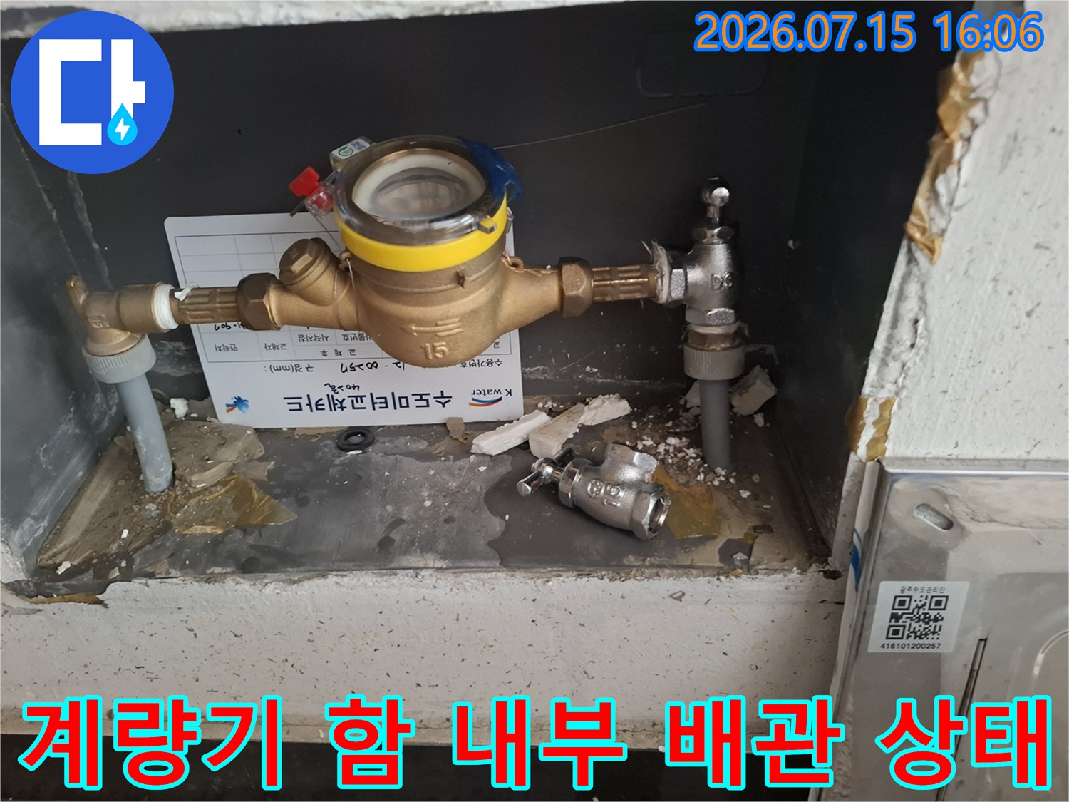 수도 계량기와 밸브 그리고 바닥에 놓인 금속 부품들이 찍힌 사진