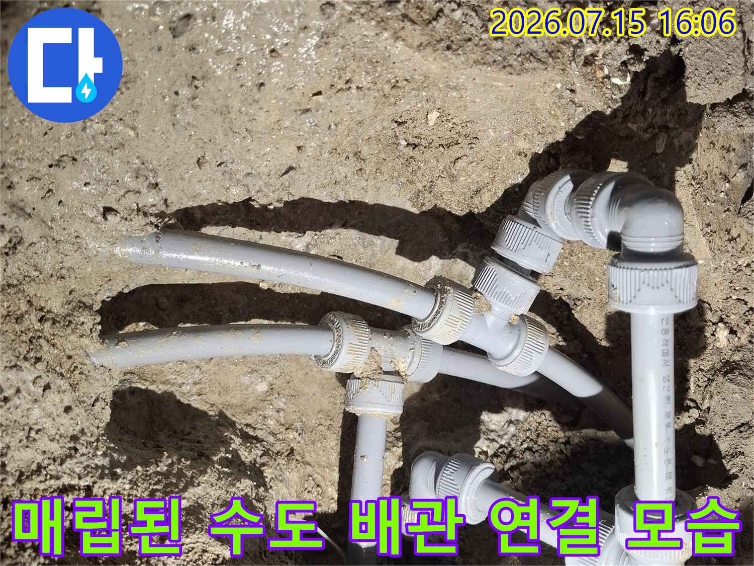 흙과 모래 속에 파묻혀 있던 회색 플라스틱 수도관들이 서로 연결되어 있는 장면