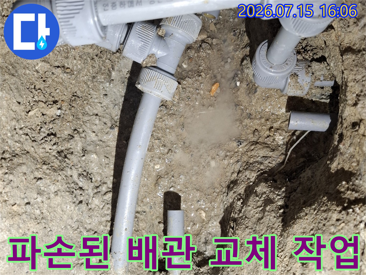 흙바닥 속에 드러난 회색빛 누수 배관과 연결 부속들-작업 현장 사진