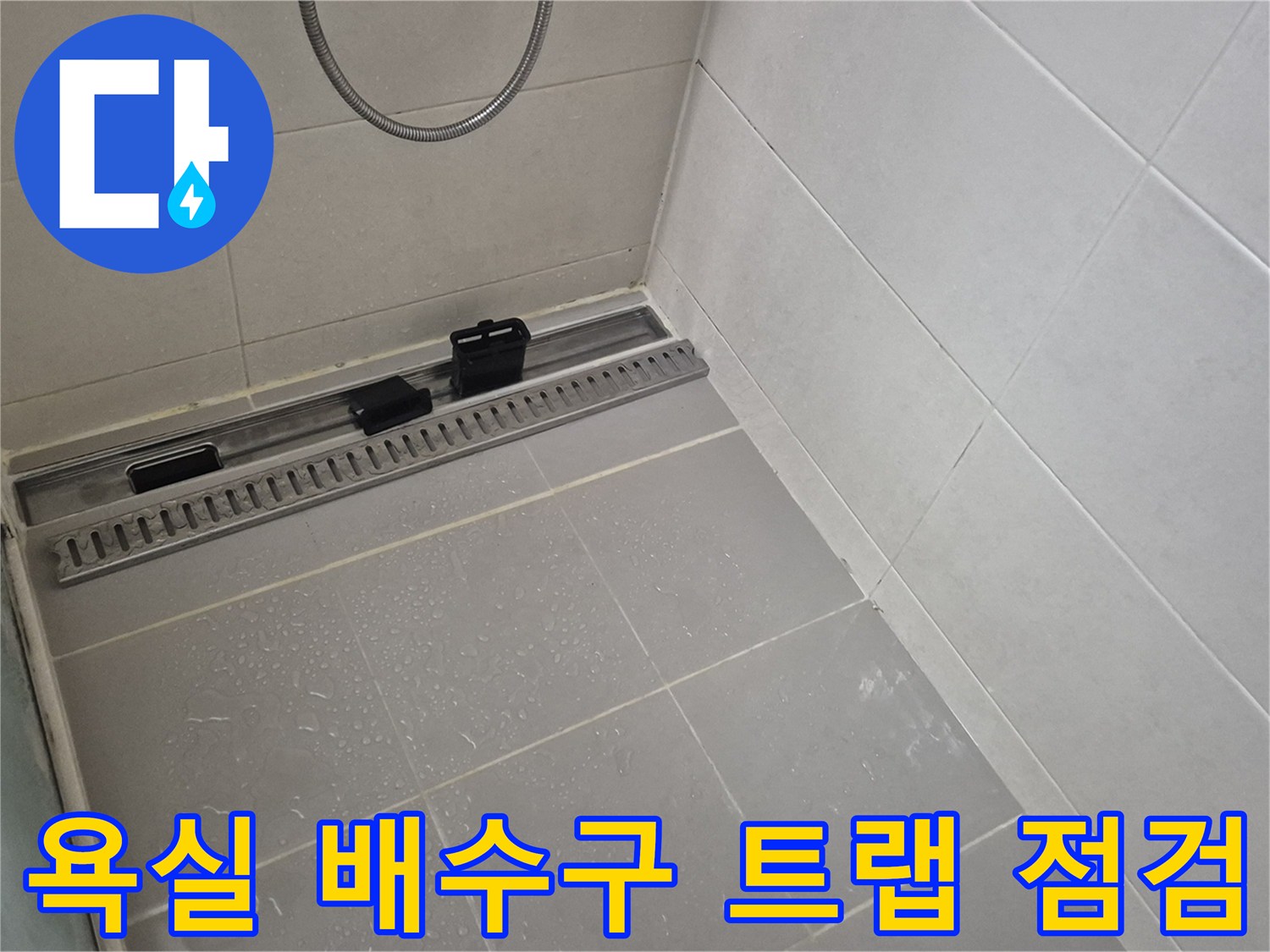 배수 트랩 주변의 타일 마감과 물 흐름 통로를 촬영한 사진입니다.