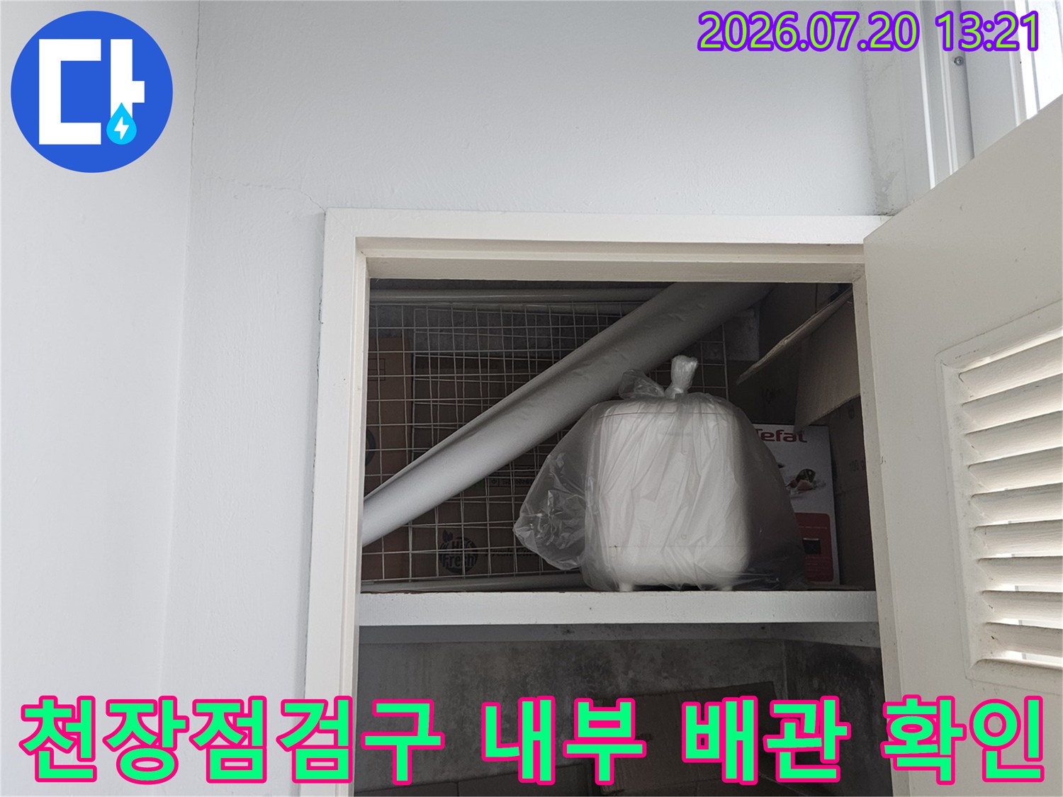 천장 점검구를 통해 내부로 노출된 배관과 주변 환경을 점검하는 모습